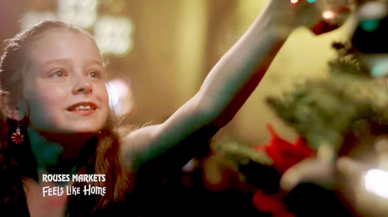screengrab of Layla putting an ornament on a Christmas tree taken from the Rouses Markets' commercial that she appears in
