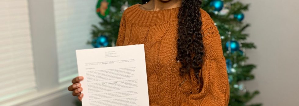 Regan Posing With Her Talent Contract In Front Of A Christmas Tree